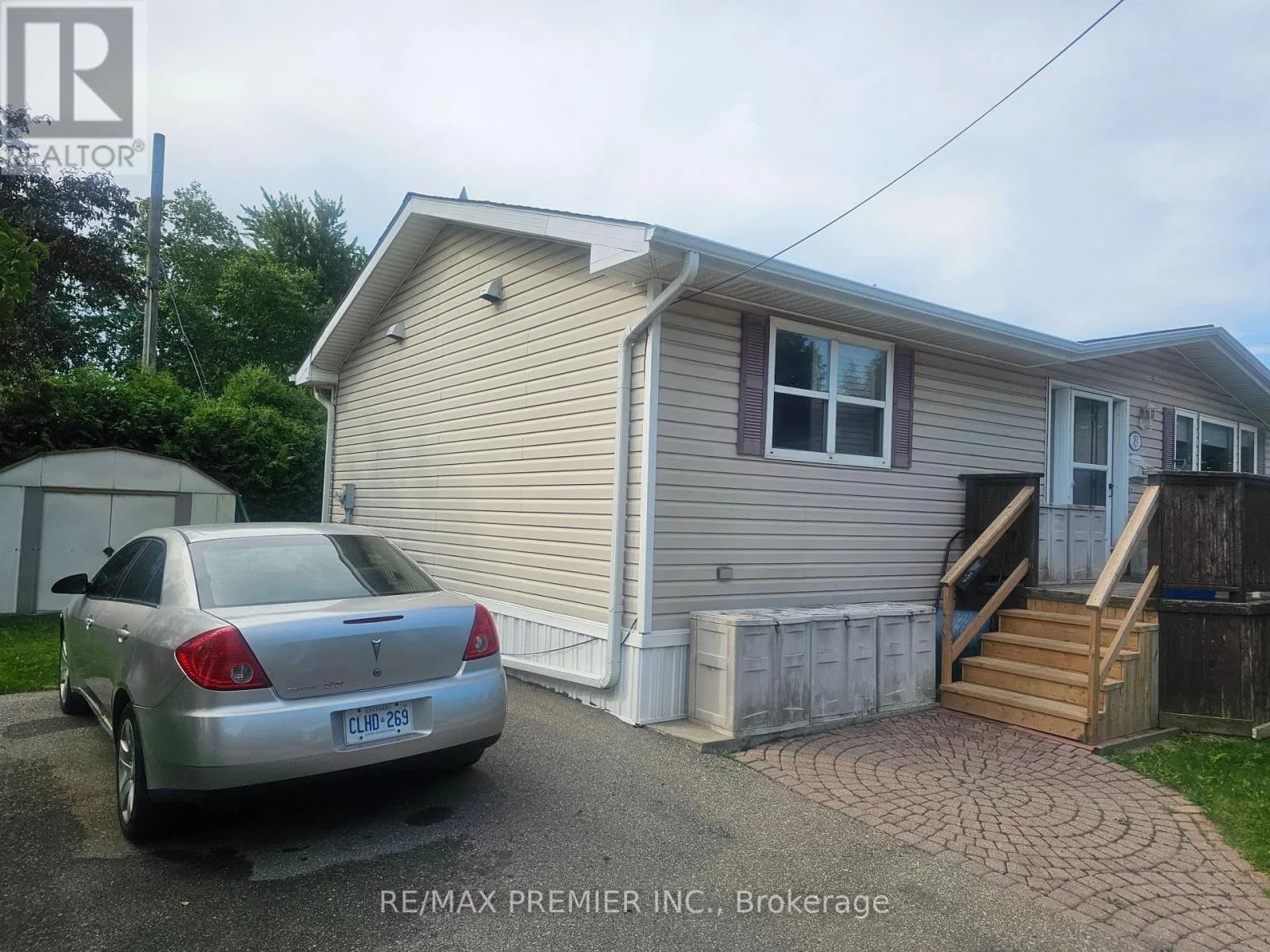 Front of 1749 Dundas Street East Unit 21, Mississauga — a beige vinyl-sided manufactured bungalow with a raised wood deck and large front windows