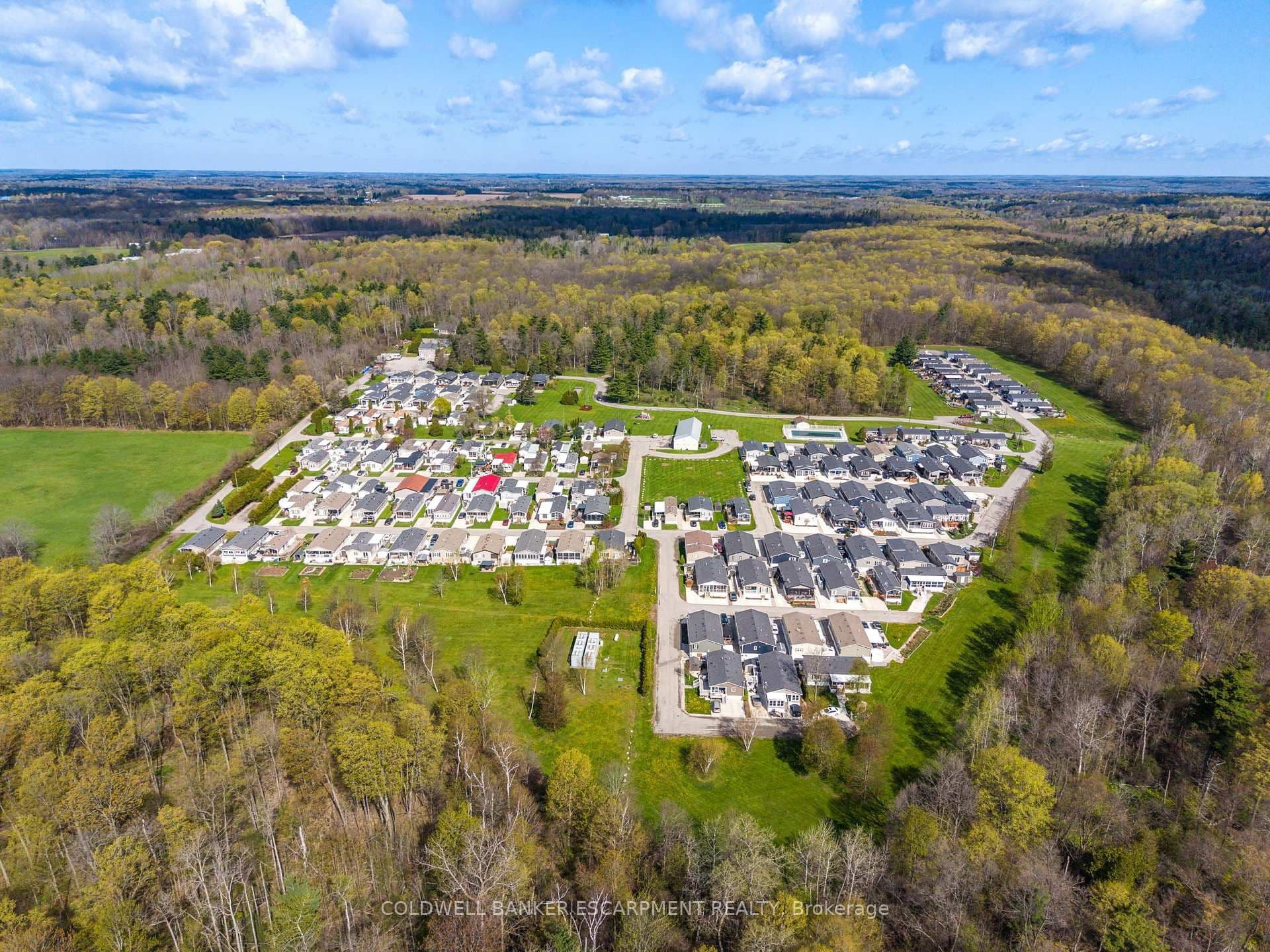 Aerial drone view of Lost Forest Park modular home community in Burlington, Ontario — wooded acreage tucked into the Niagara Escarpment with rows of single-family modular homes